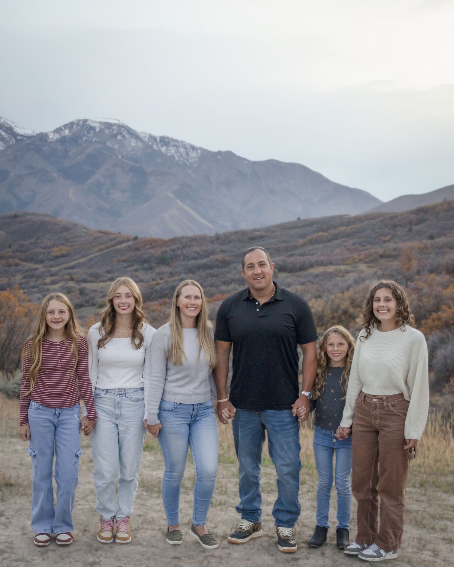 A group of people stand together in a line against a backdrop of rugged mountain scenery during autumn.