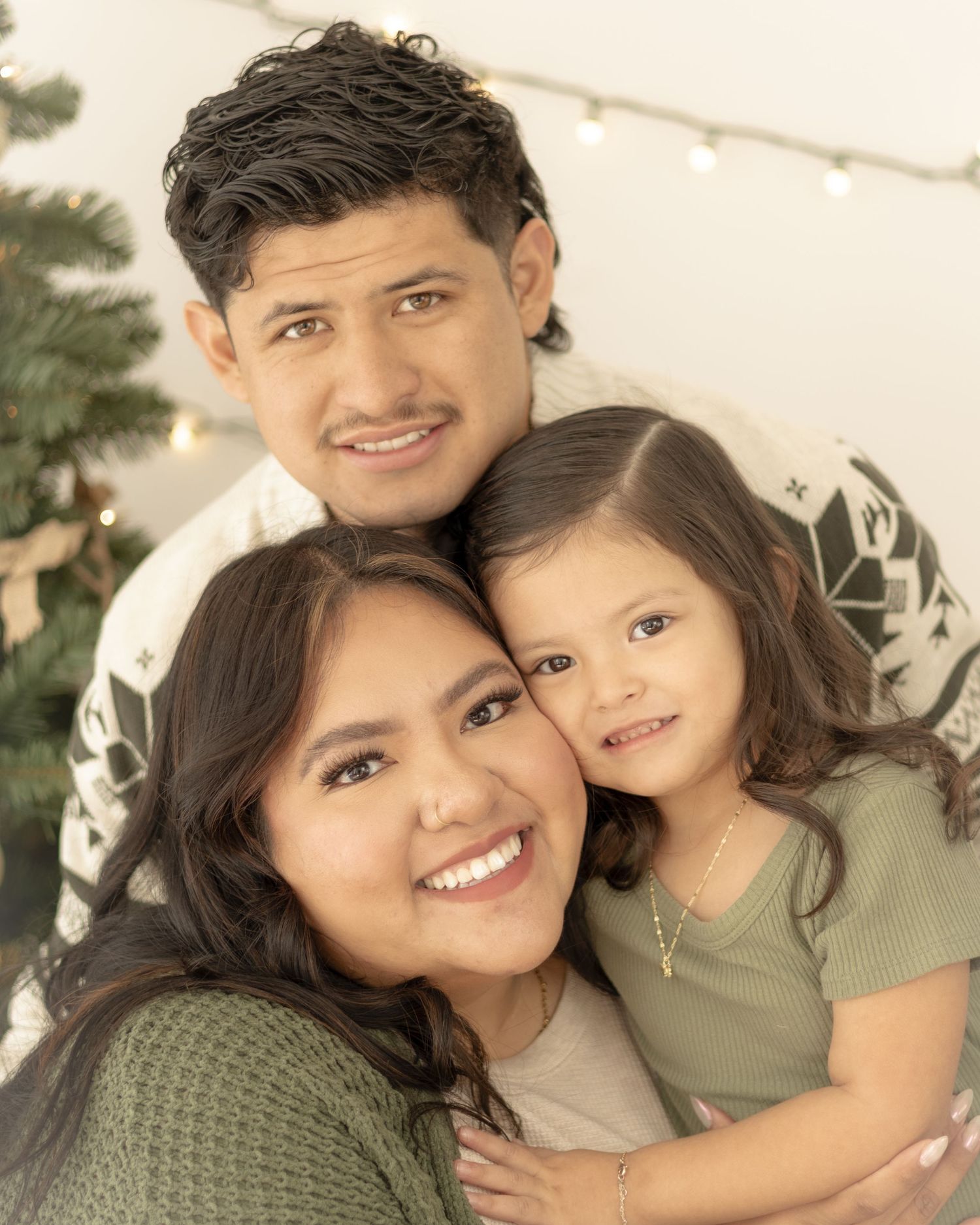 A family poses together in coordinated olive green outfits for a warm and intimate portrait session.