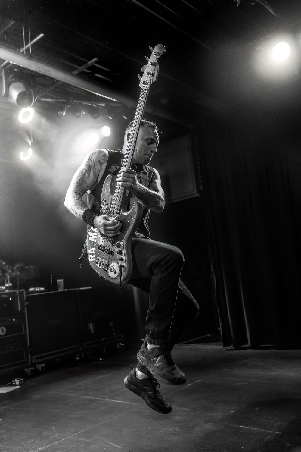 Black and white photo series of a musician performing energetically on stage with a guitar under dramatic lighting.
