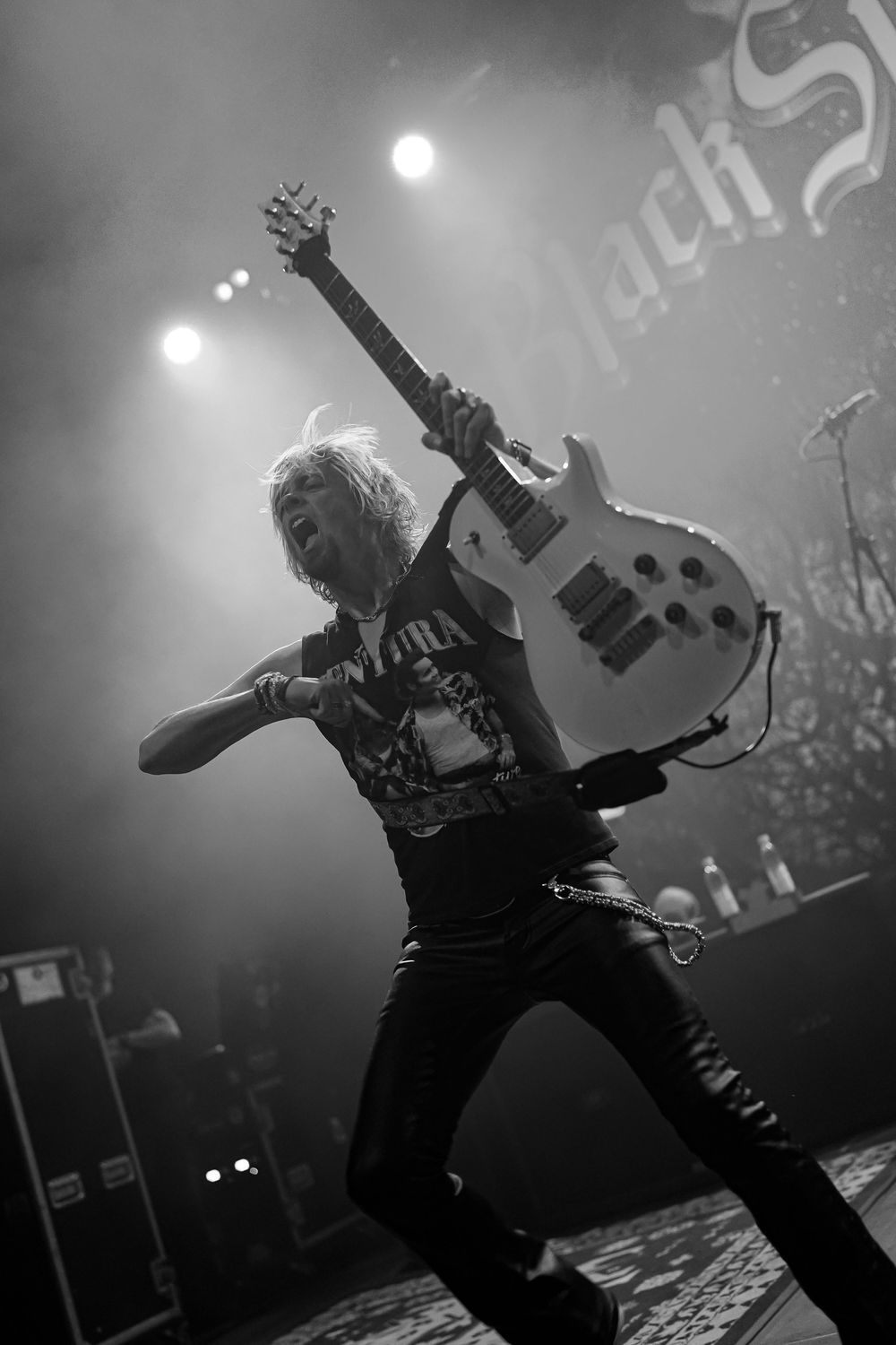 Black and white photos of a guitarist performing on stage in dramatic silhouette with moody concert lighting.