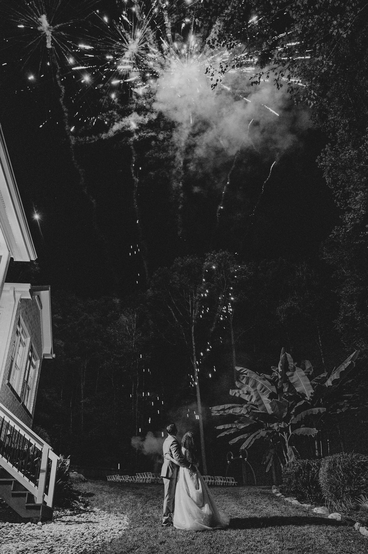 Fireworks light up the night sky in black and white, creating a dramatic display against the dark background.