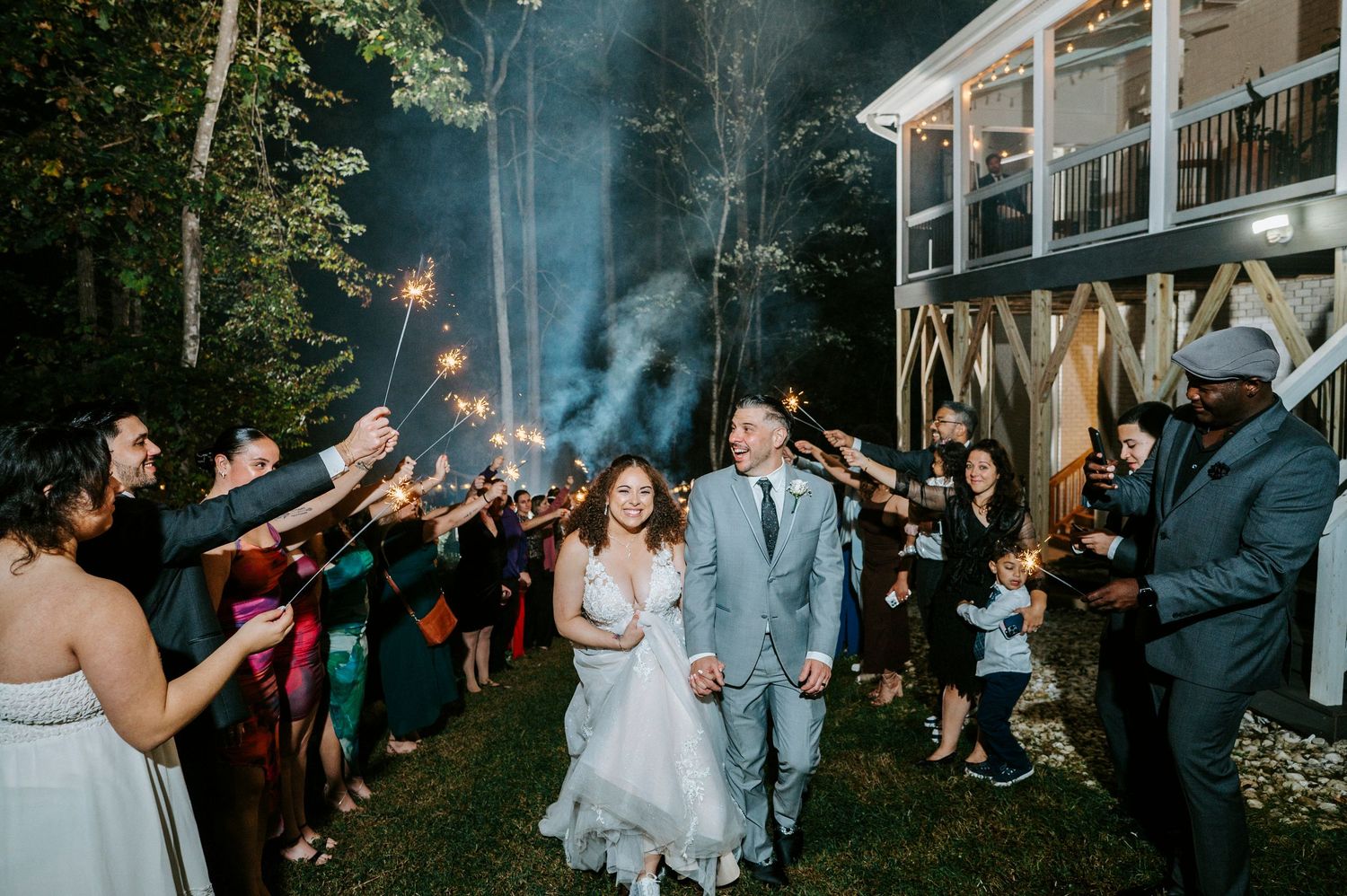 Wedding guests celebrate with sparklers during an outdoor evening reception celebration.