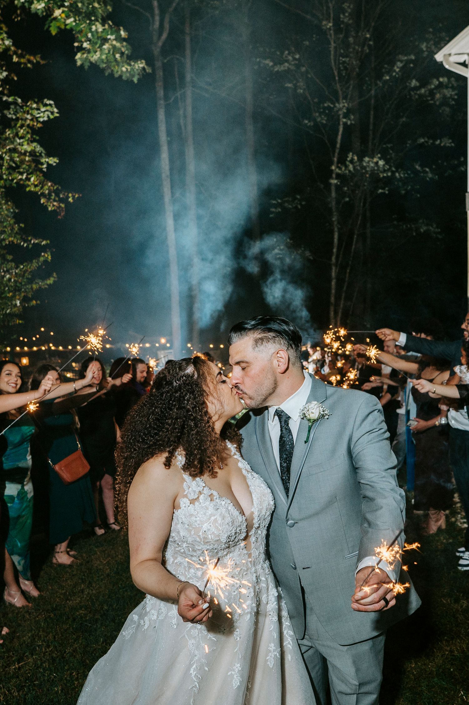Wedding couple shares a romantic dance moment under twinkling lights at an evening outdoor reception.