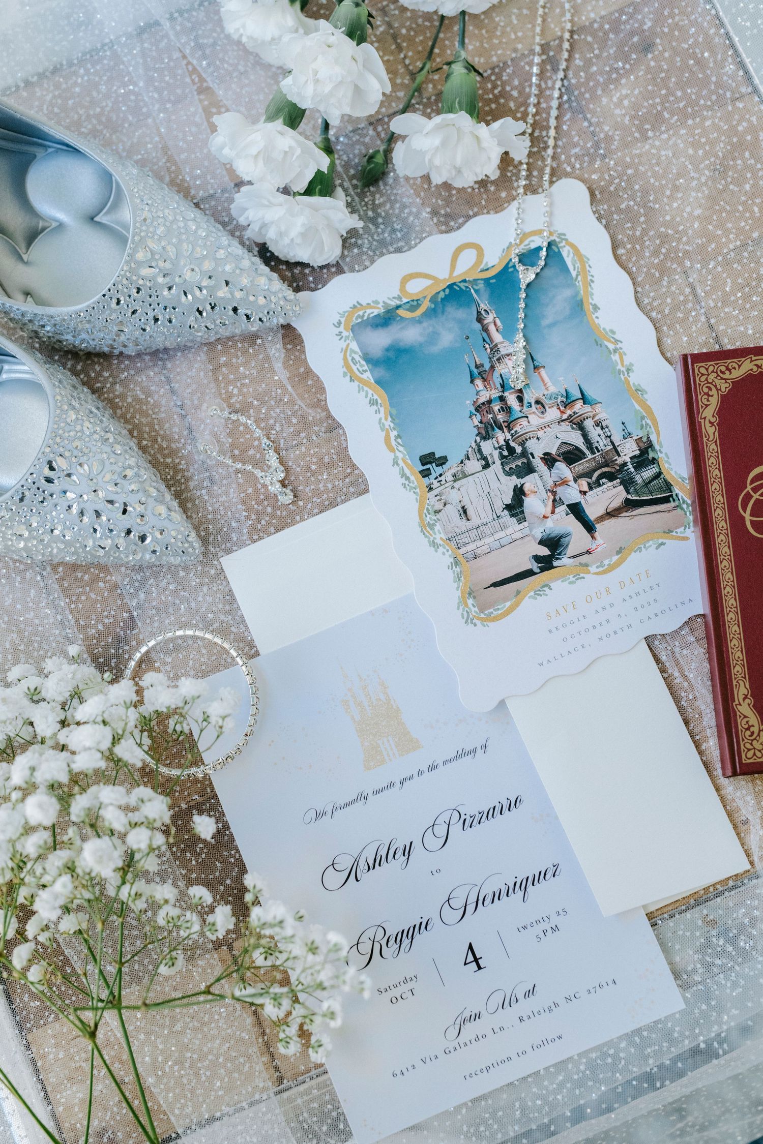 Elegant wedding invitations with white flowers and lace details arranged on a sparkly surface.