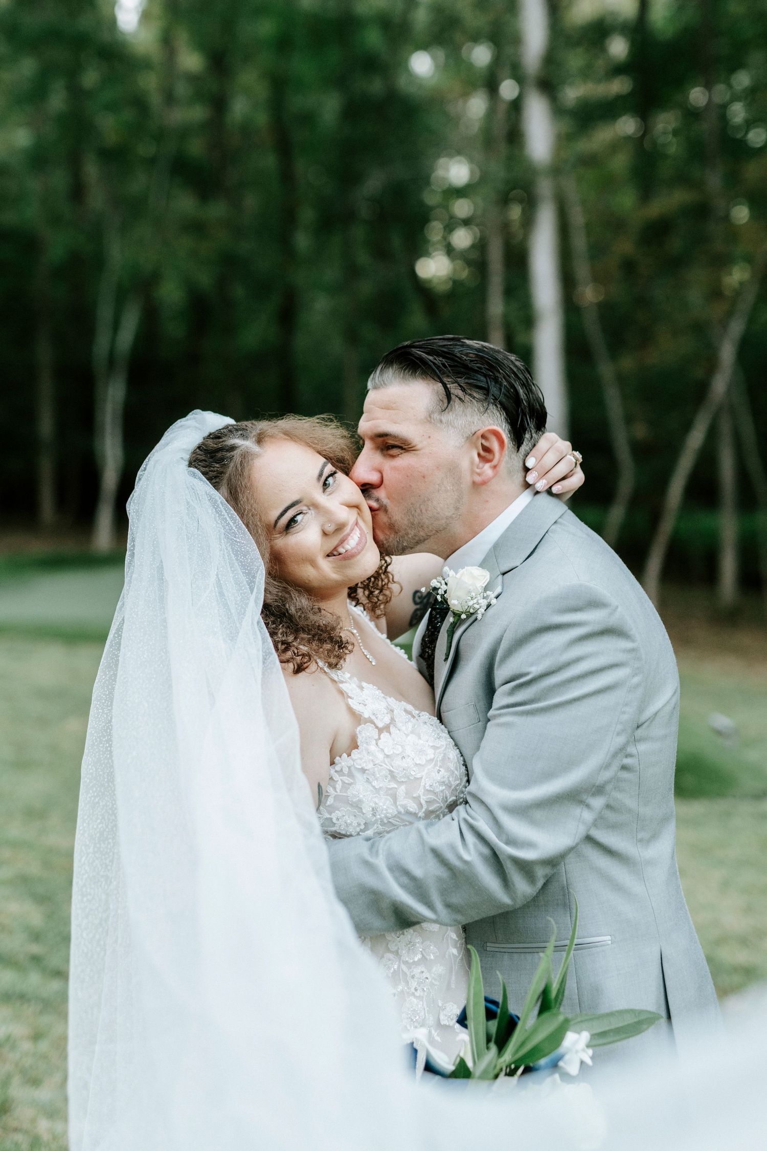 Romantic wedding portraits show tender moments between newlyweds in a wooded outdoor setting.