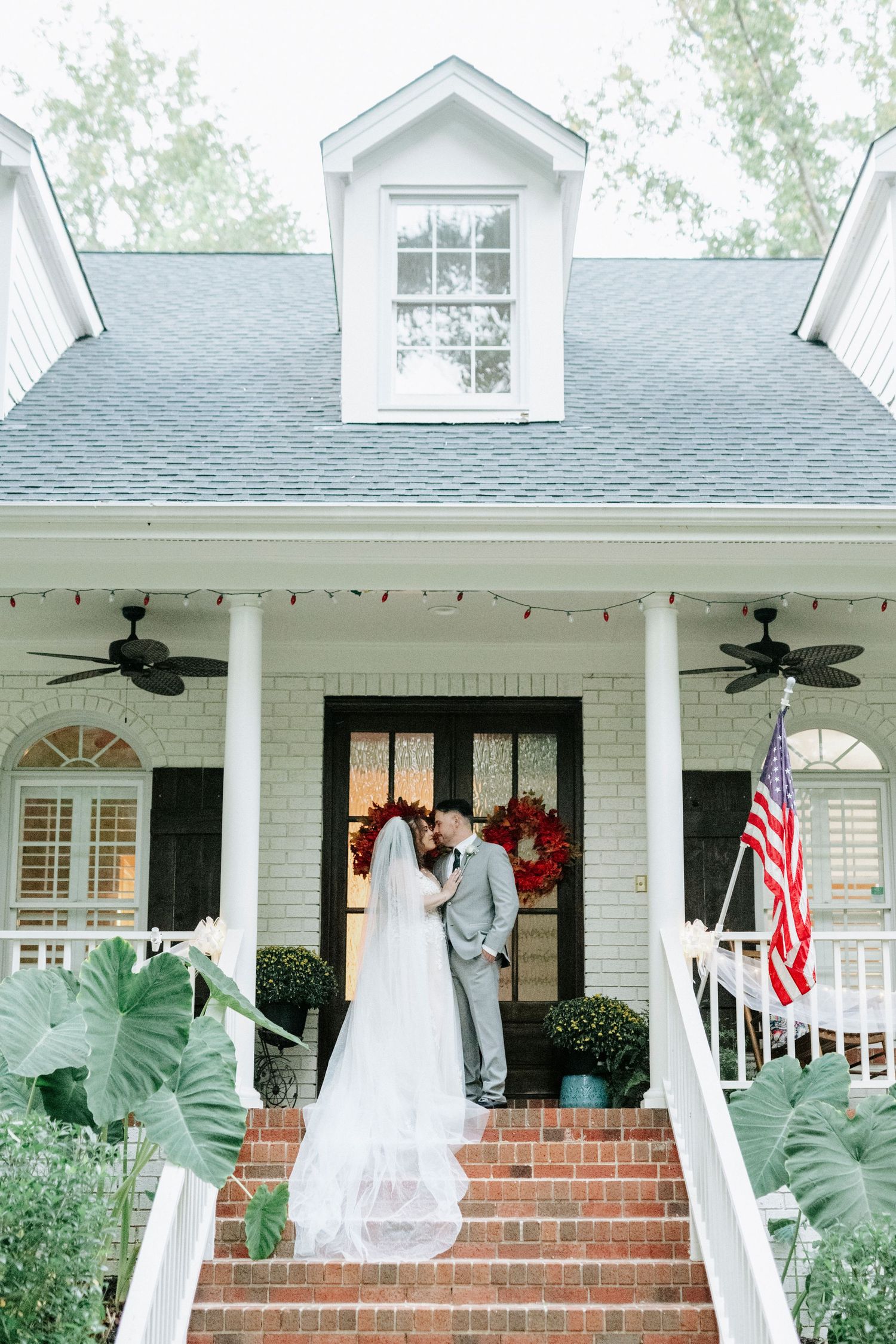 White colonial style house with front porch decorated for a wedding celebration.