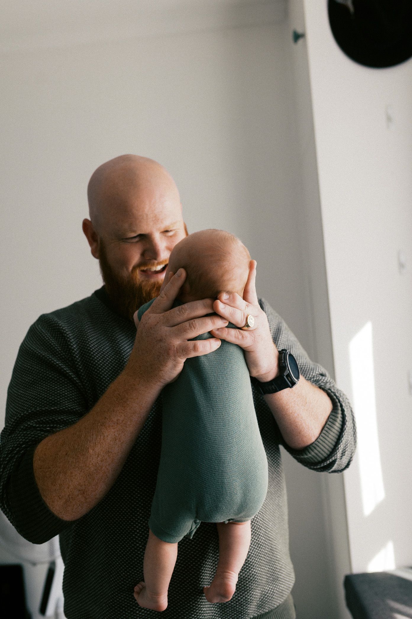 A sequence of tender moments between a parent and baby in a minimalist white room.