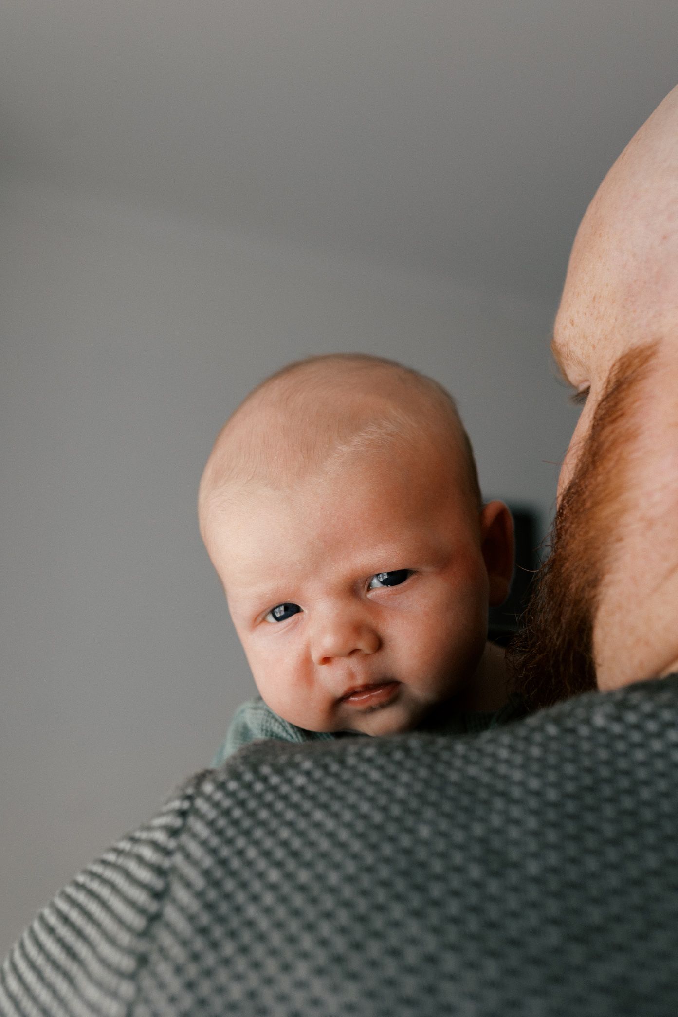 A series of close-up photos showing a baby peeking over a gray textured surface in different poses.
