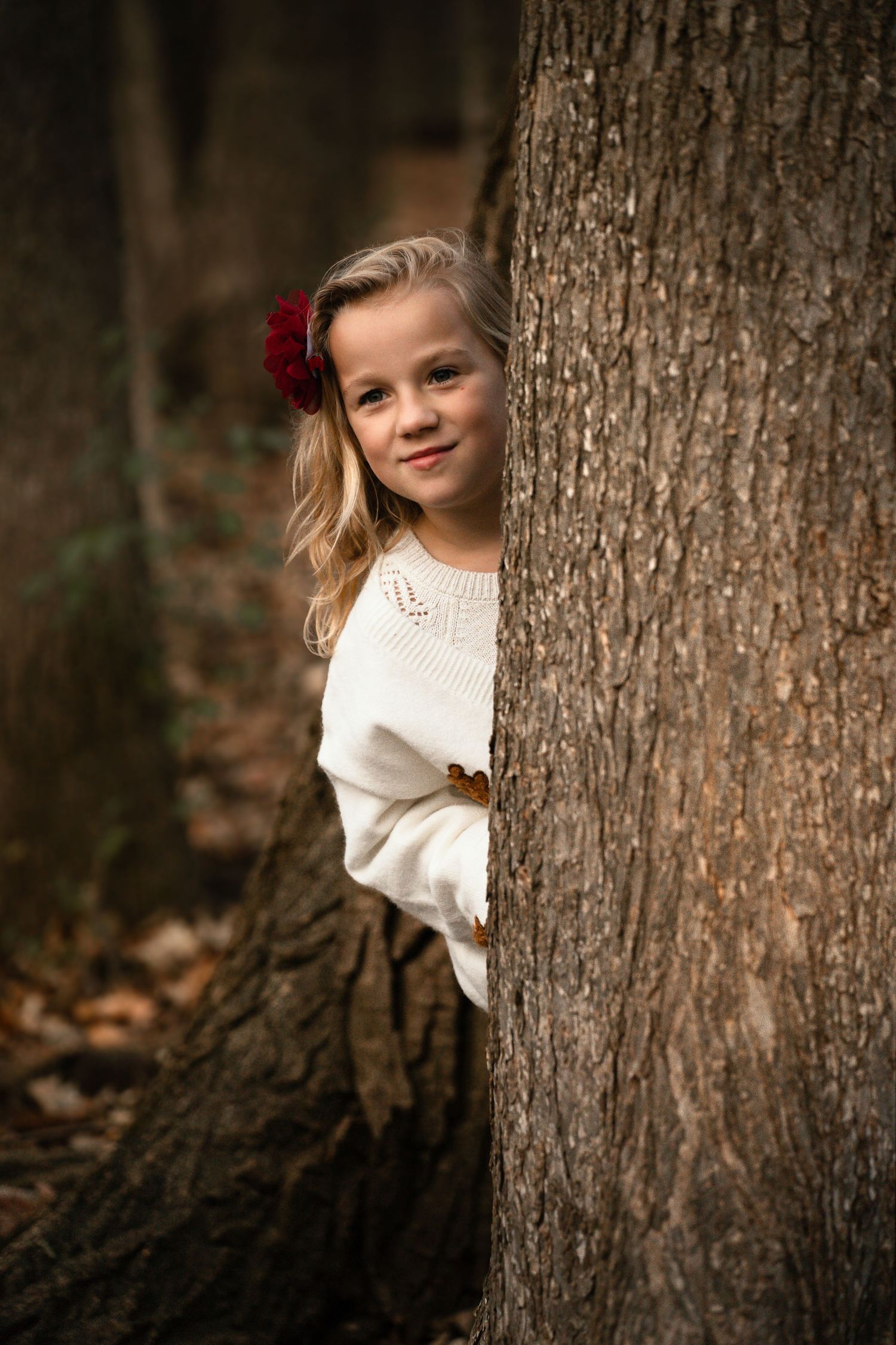 Playful portrait series of someone peeking from behind a large tree trunk.