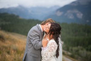 Bride and groom share a romantic moment with stunning Rocky Mountain scenery in the background during their outdoor wedding.