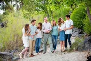 A group of people laugh and smile together while walking along a nature trail on a sunny day.