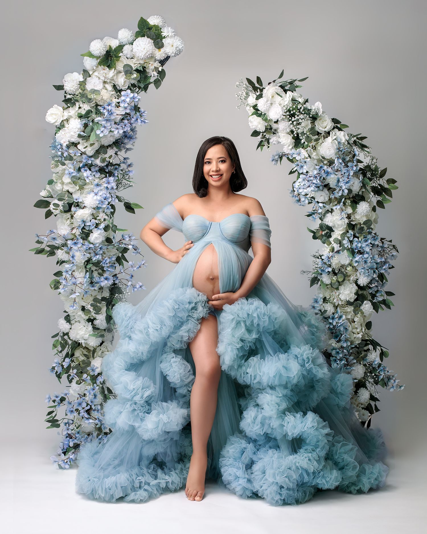 Glamorous pregnant woman in a dreamy powder blue couture dress, captured in fine art style by Caz Captures.