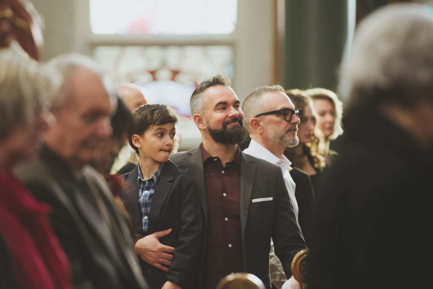 People standing in a crowd listening intently during what appears to be an indoor gathering or event.