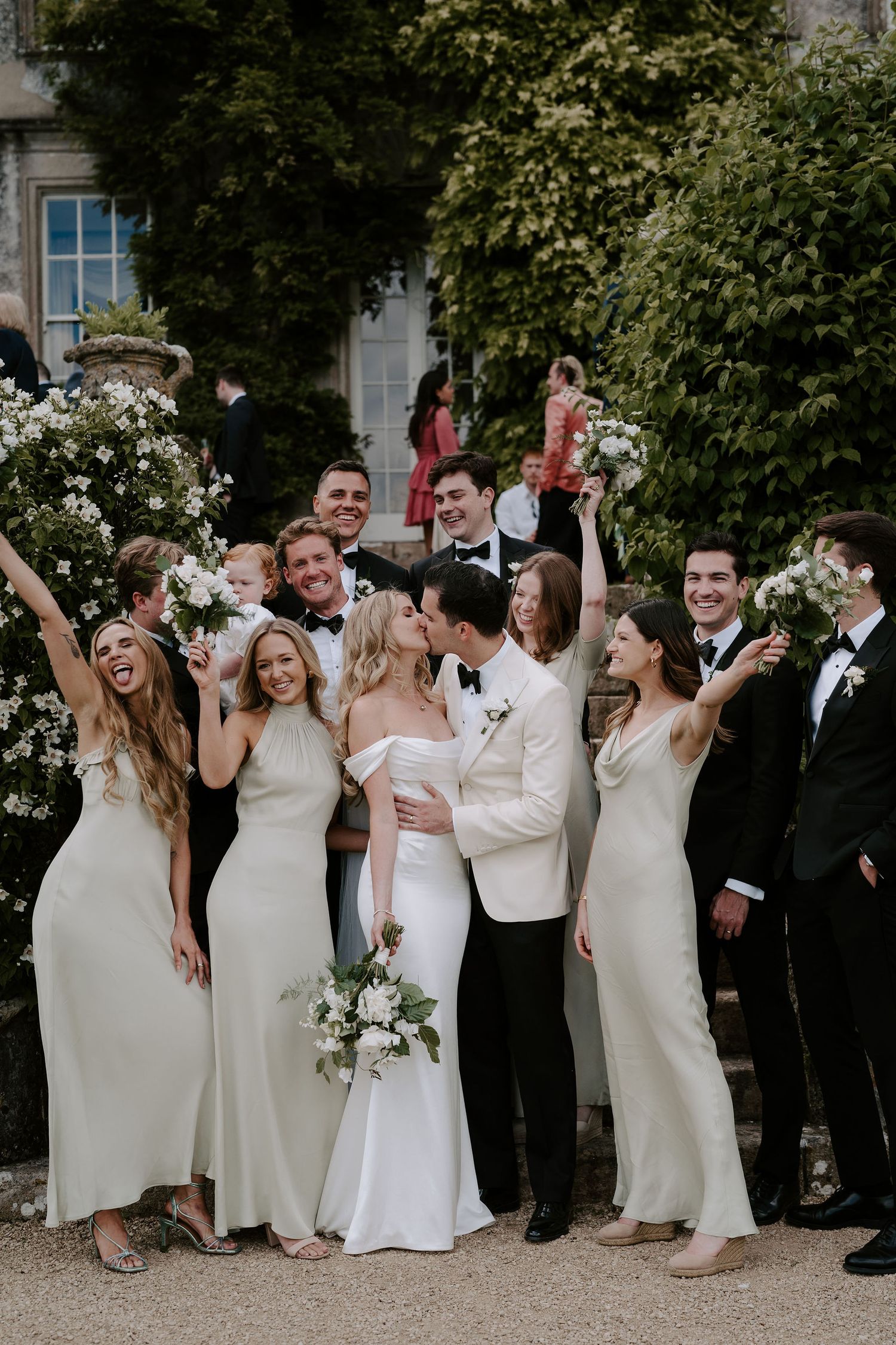 bride and groom kissing while surrounded by bridal party at hamswell house wedding in bath