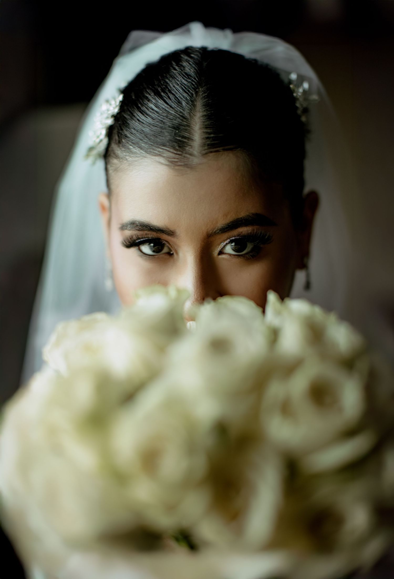 A dramatic bridal portrait with white roses and an elegant veil.