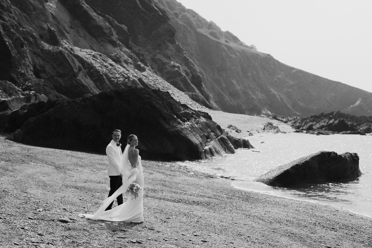 Bride and Groom walking along beach at Tunnels beach wedding venue in north devon
