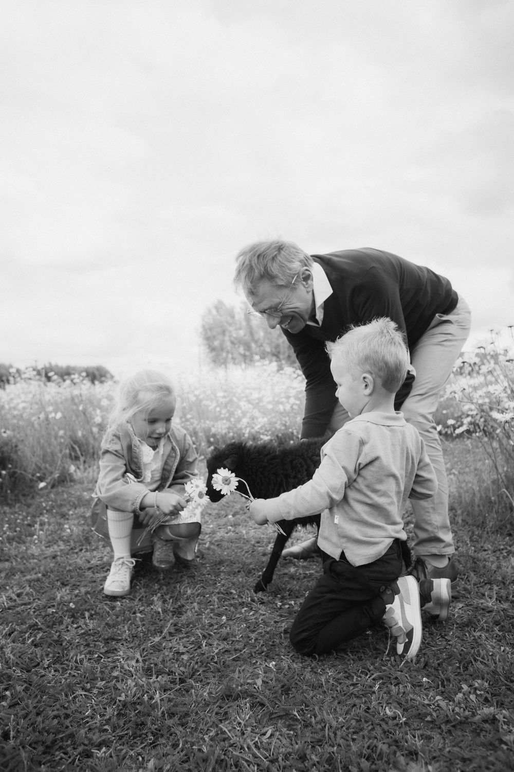Grootouder en kleinkinderen in een bloemenveld.