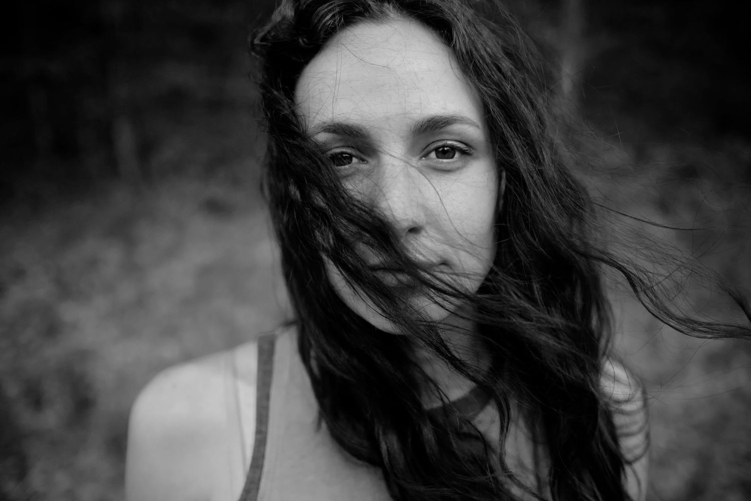 Artistic black and white portrait of a woman with windswept dark hair.