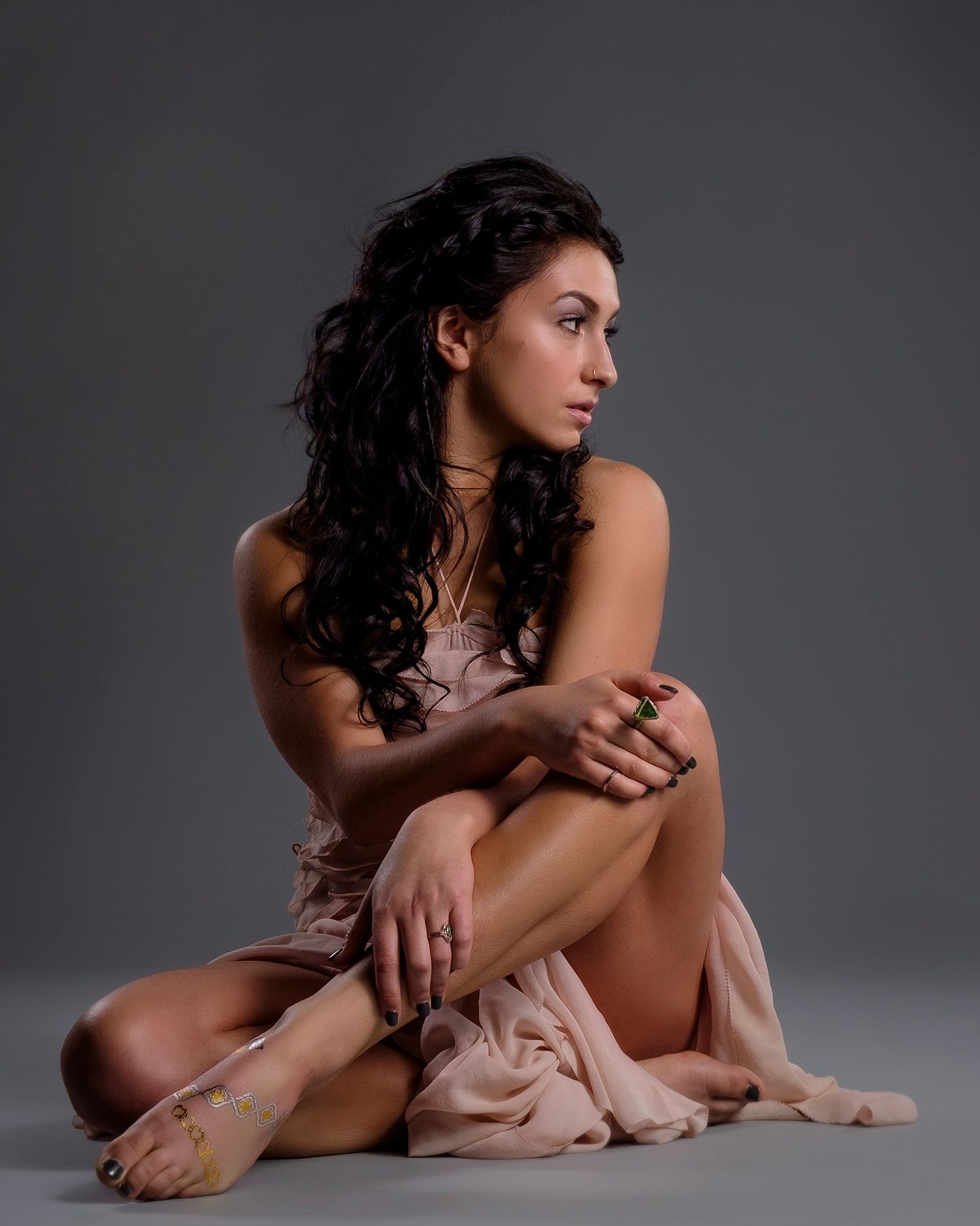 Artistic portrait of a person in romantic pose wearing flowing fabric against gray background.