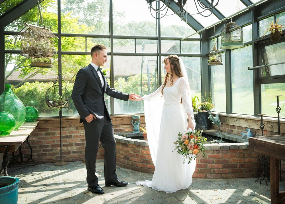 Indoor greenhouse venue decorated for a wedding ceremony with brick walls and glass ceiling.