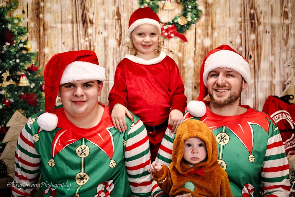 Holiday portrait of people wearing festive elf and Santa outfits with striped sleeves against rustic wooden background.