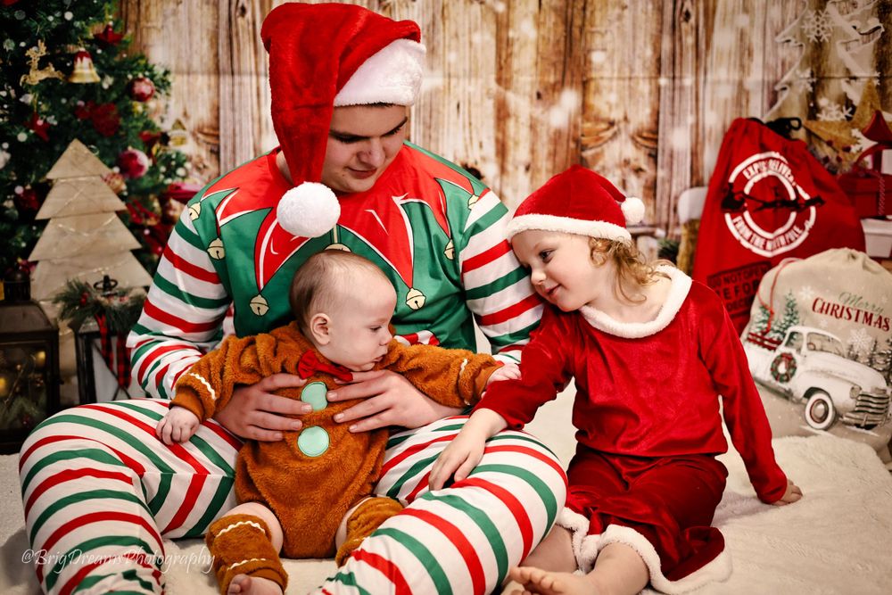 Holiday scene with striped pajamas and Santa hats around a decorated Christmas tree with wooden background.
