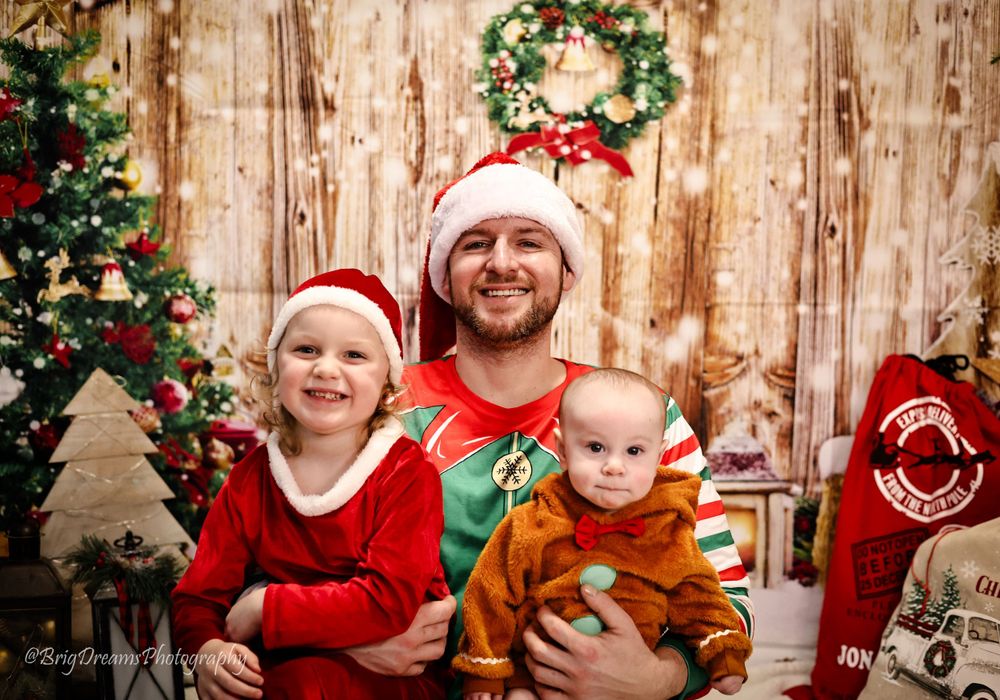 Festive holiday photo with Santa hats against wooden backdrop with Christmas tree and wreath decorations.