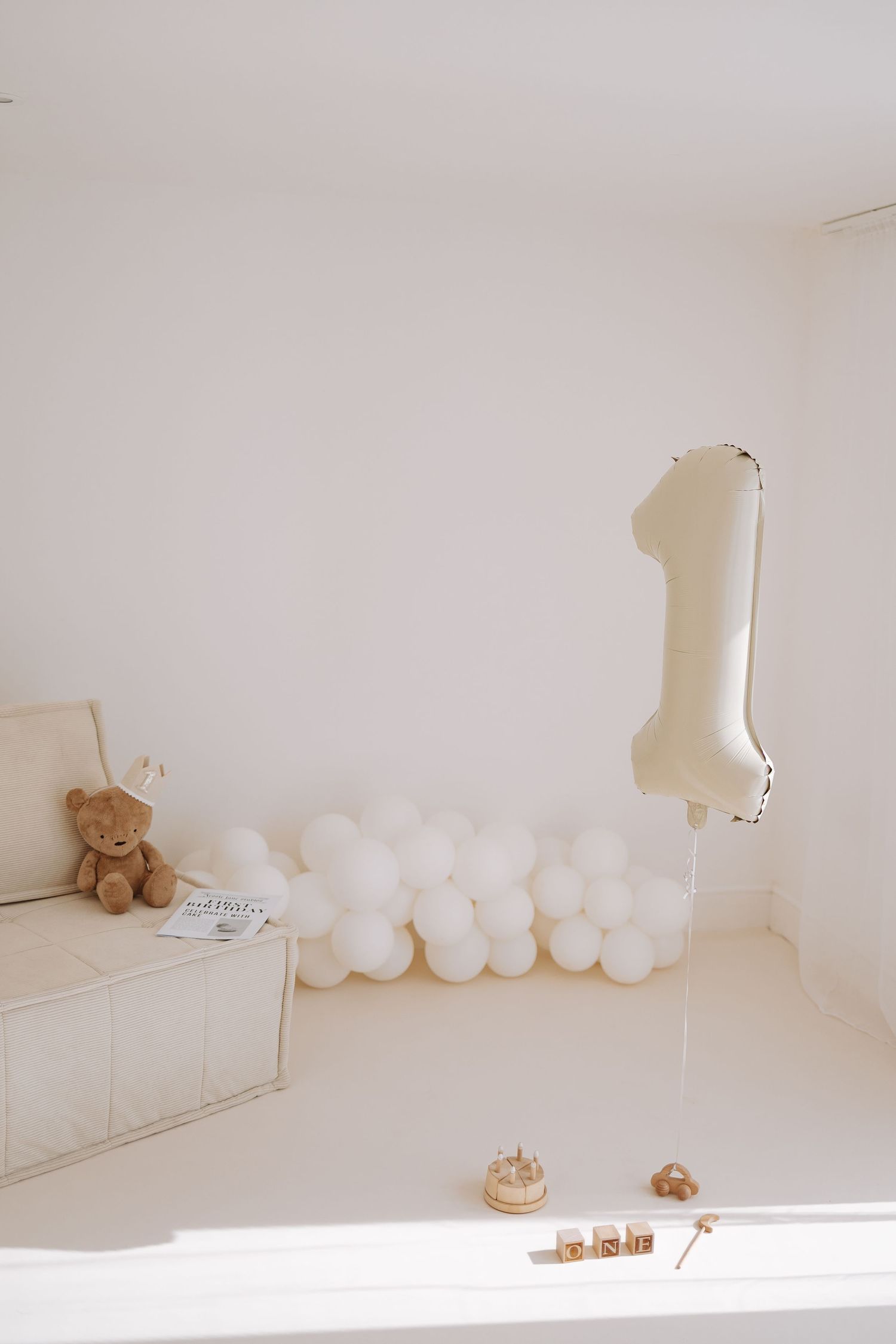 Baby enjoying cake smash photo session with light blue and gold balloon backdrop and white cake stand.