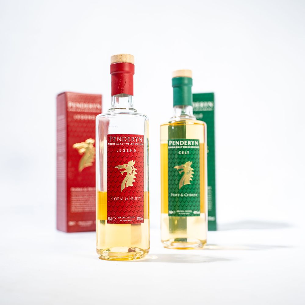 Three bottles of Penderyn Welsh whisky displayed with their red and green retail packaging against white backdrop.