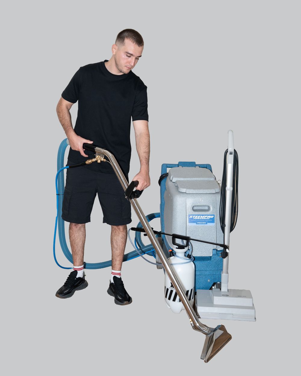 A person in black clothing demonstrates the steps of using a carpet cleaning machine from different angles.