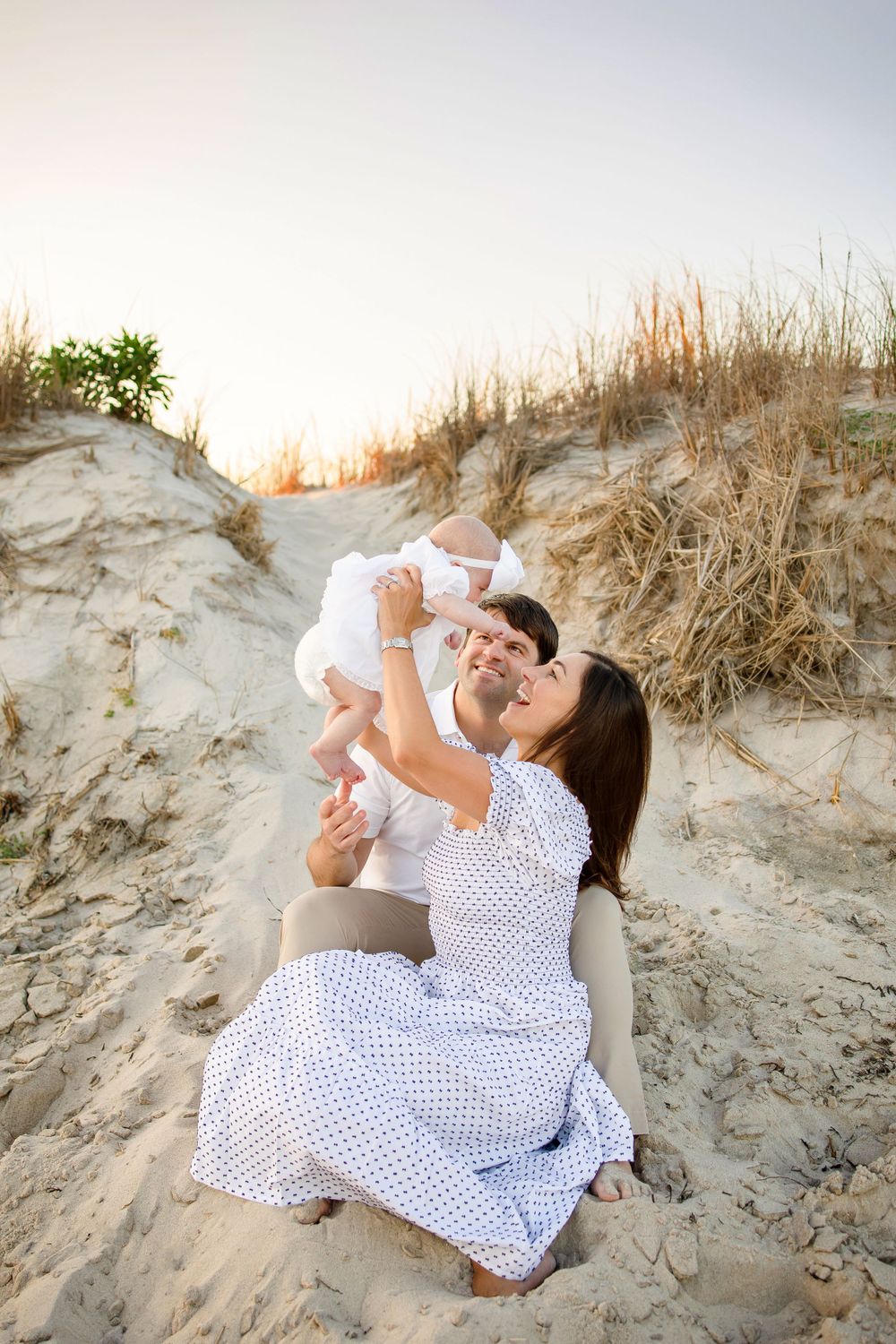 A tender family moment captured on sandy dunes during golden hour.