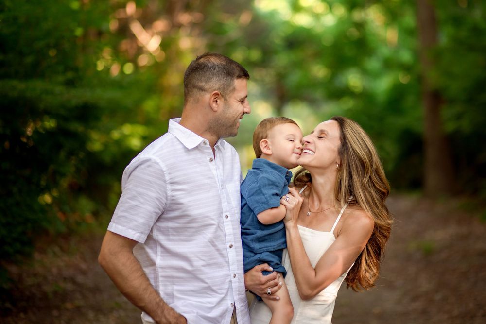 Intimate family moment captured in a wooded setting with soft natural lighting.