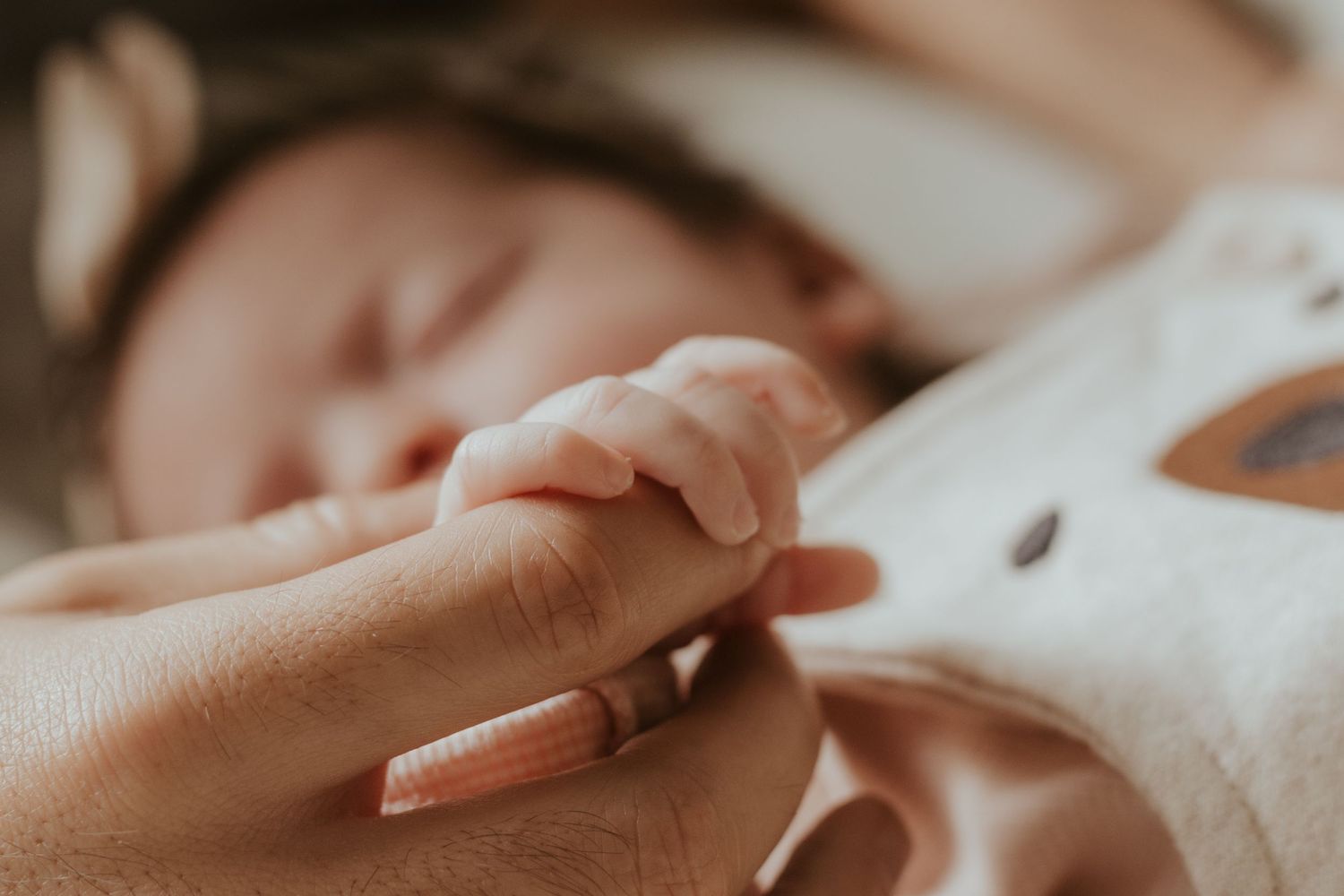 close up of a mother's hand holding her new born baby's hand