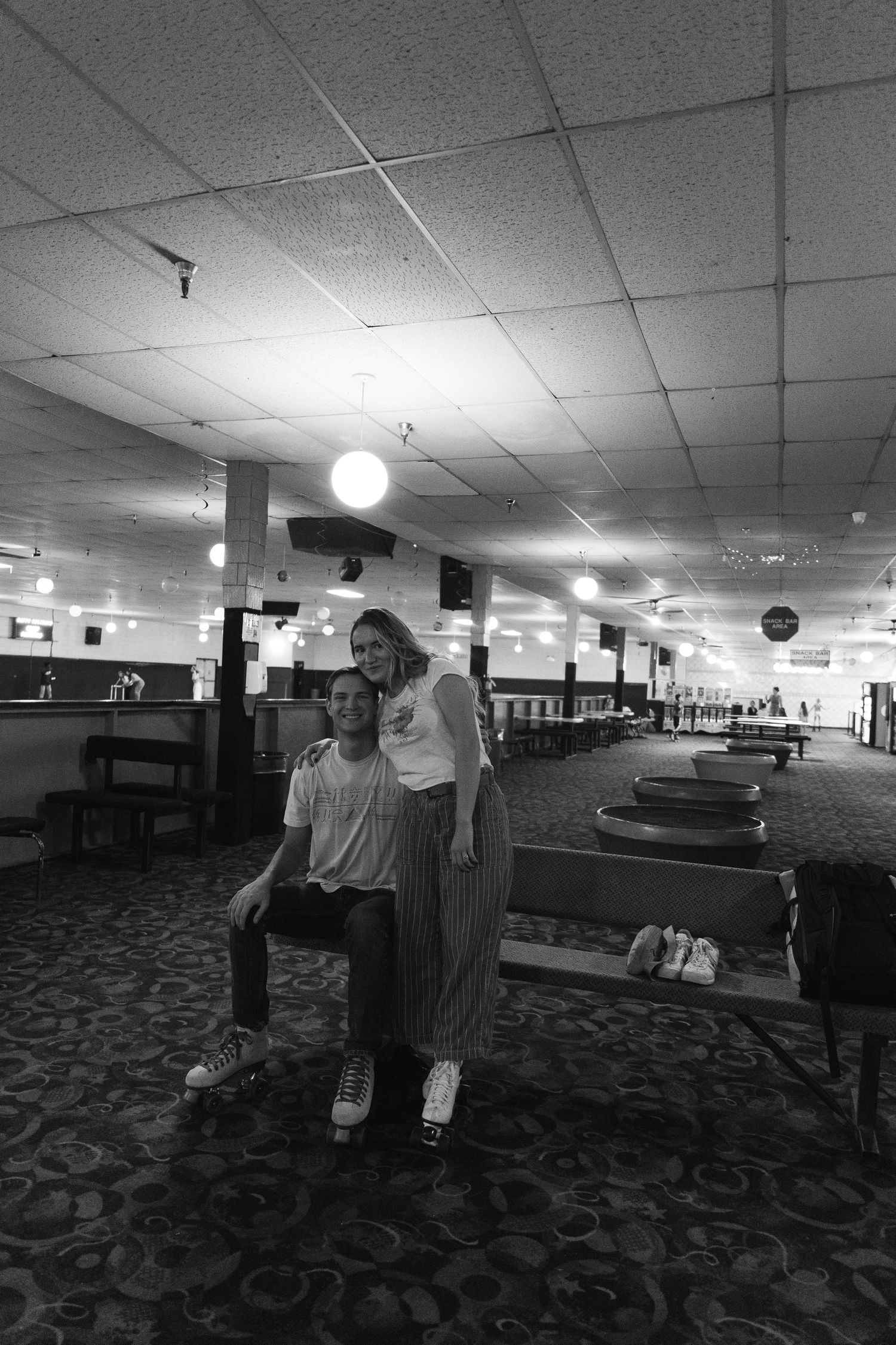 Black and white photo showing two people at a bowling alley with retro carpeting and vintage lane architecture.