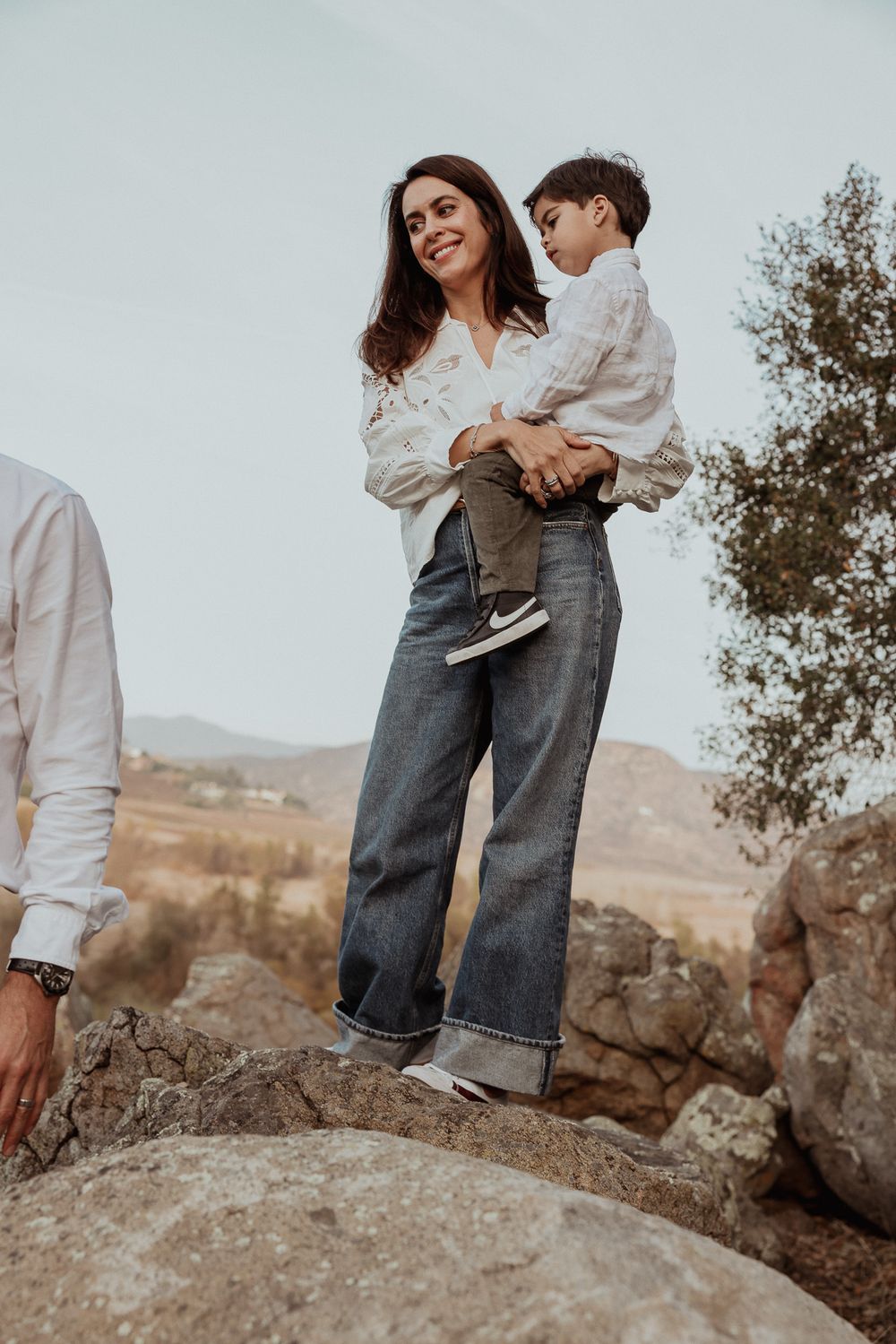 Mother and child standing on rocky outcrop with desert landscape behind.