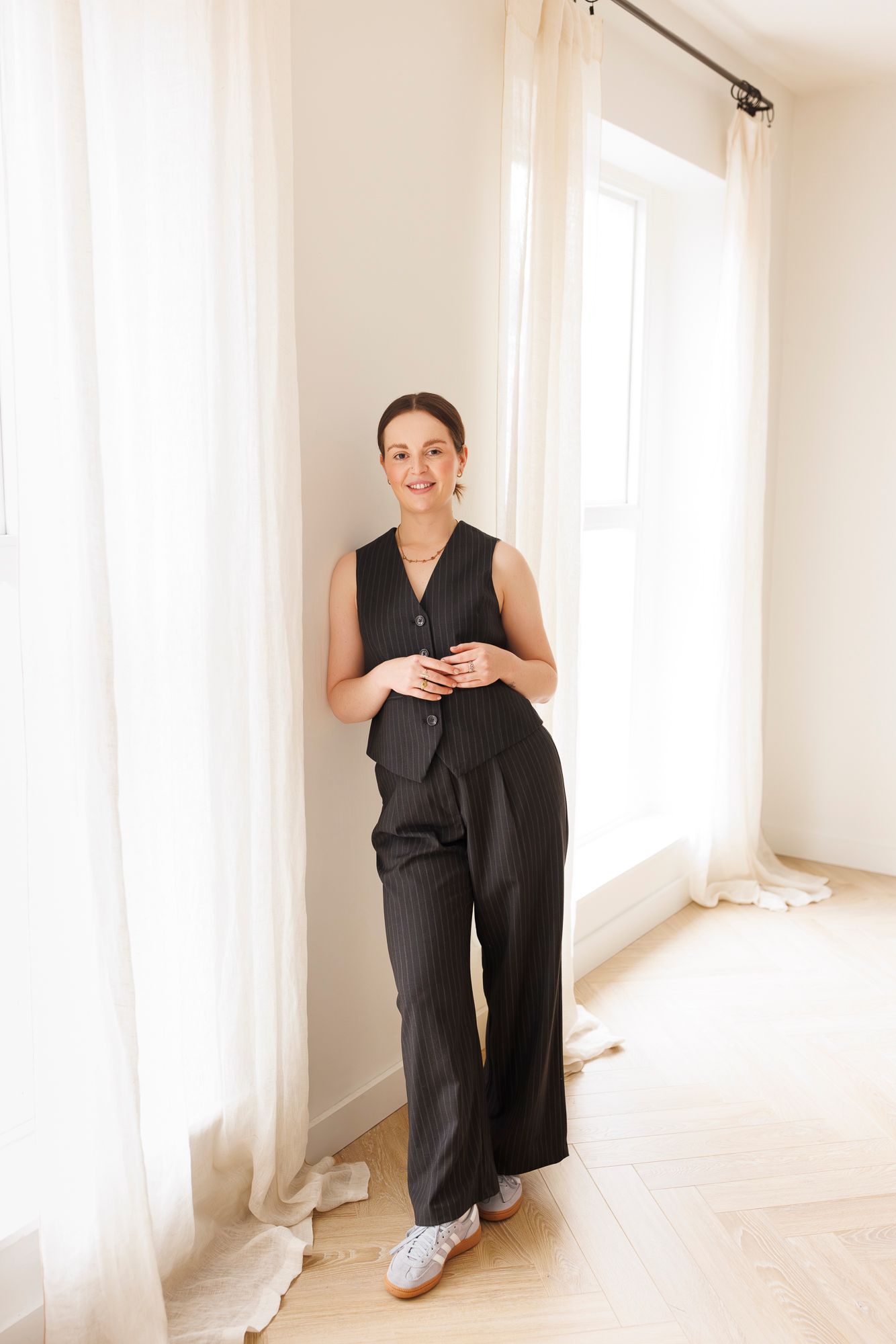 Business professional in black sleeveless outfit standing by bright window. Personal Branding Photography.