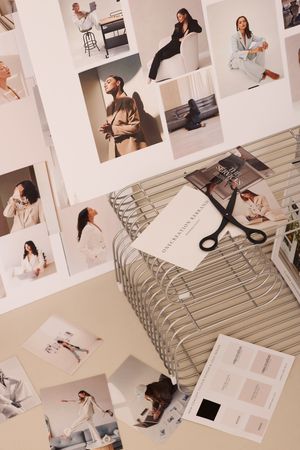 Flatlay of fashion photography prints and creative materials spread out on textured surface.