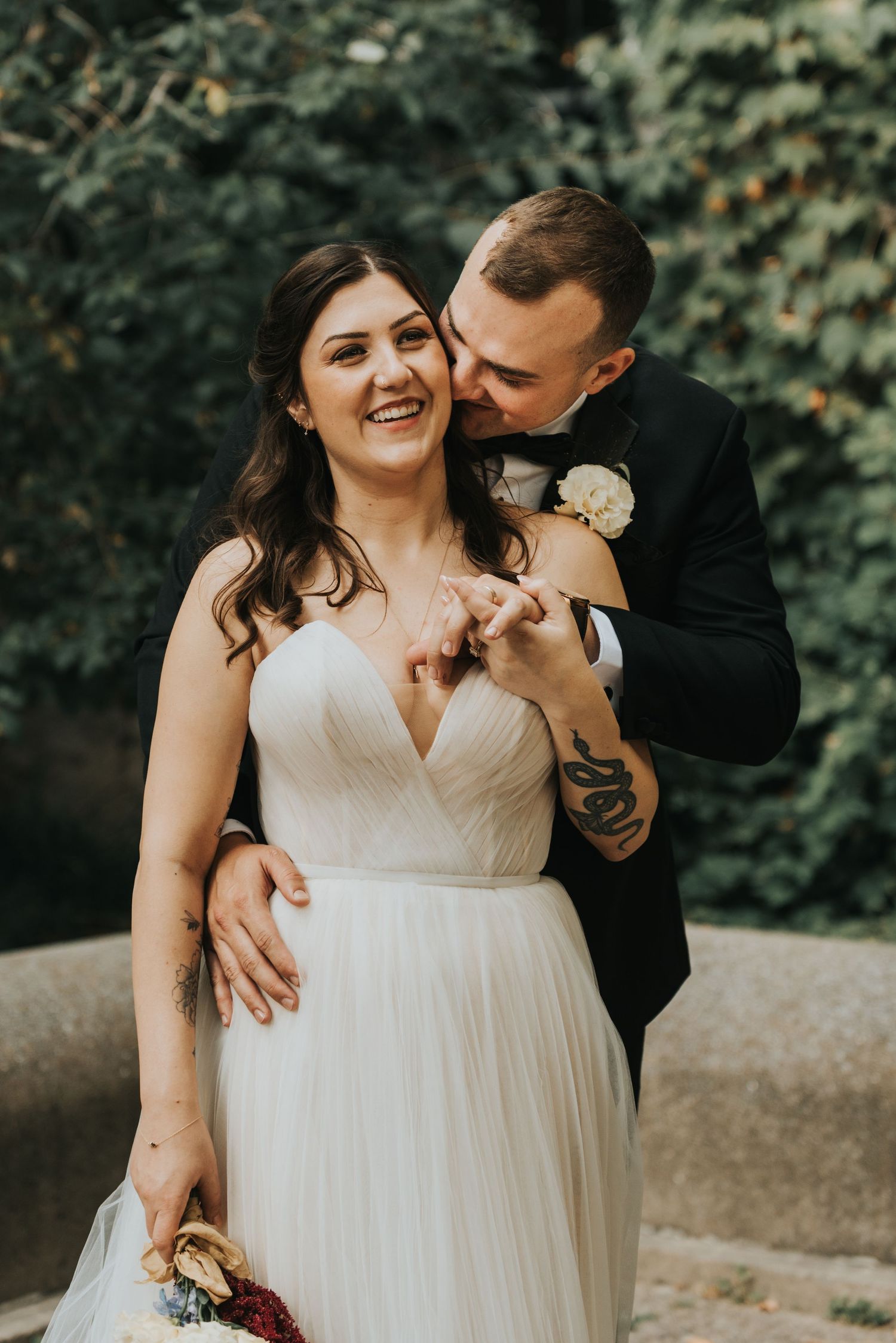 Natural candid wedding photo capturing laughter and joy between newlyweds in an outdoor garden setting.