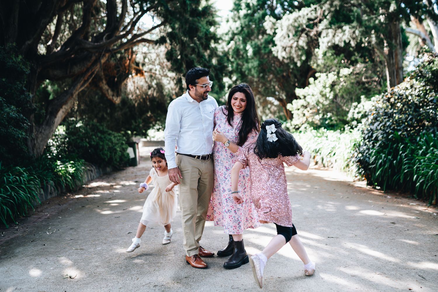 A happy family of 4 in Melbourne's St Kilda Botanical Gardens with lush greeneries as backdrop taken by a Melbourne family photographer.