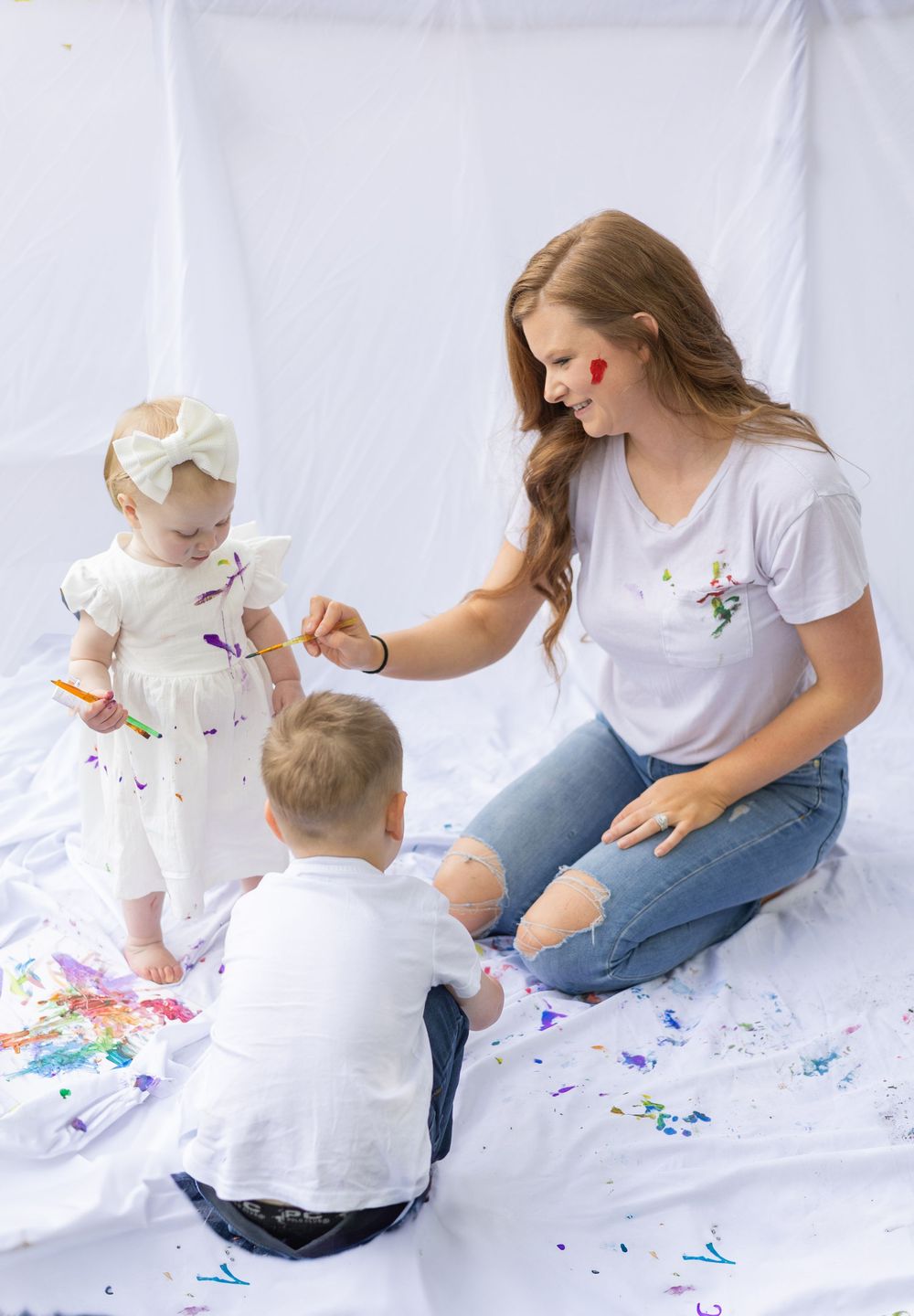A joyful indoor art activity with bright paint colors creating a fun and messy creative experience on white sheets.