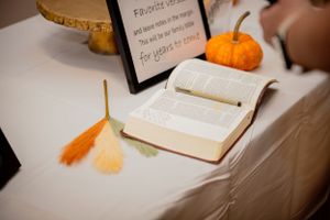 Open book with autumn pumpkin decor and fall themed wedding details.