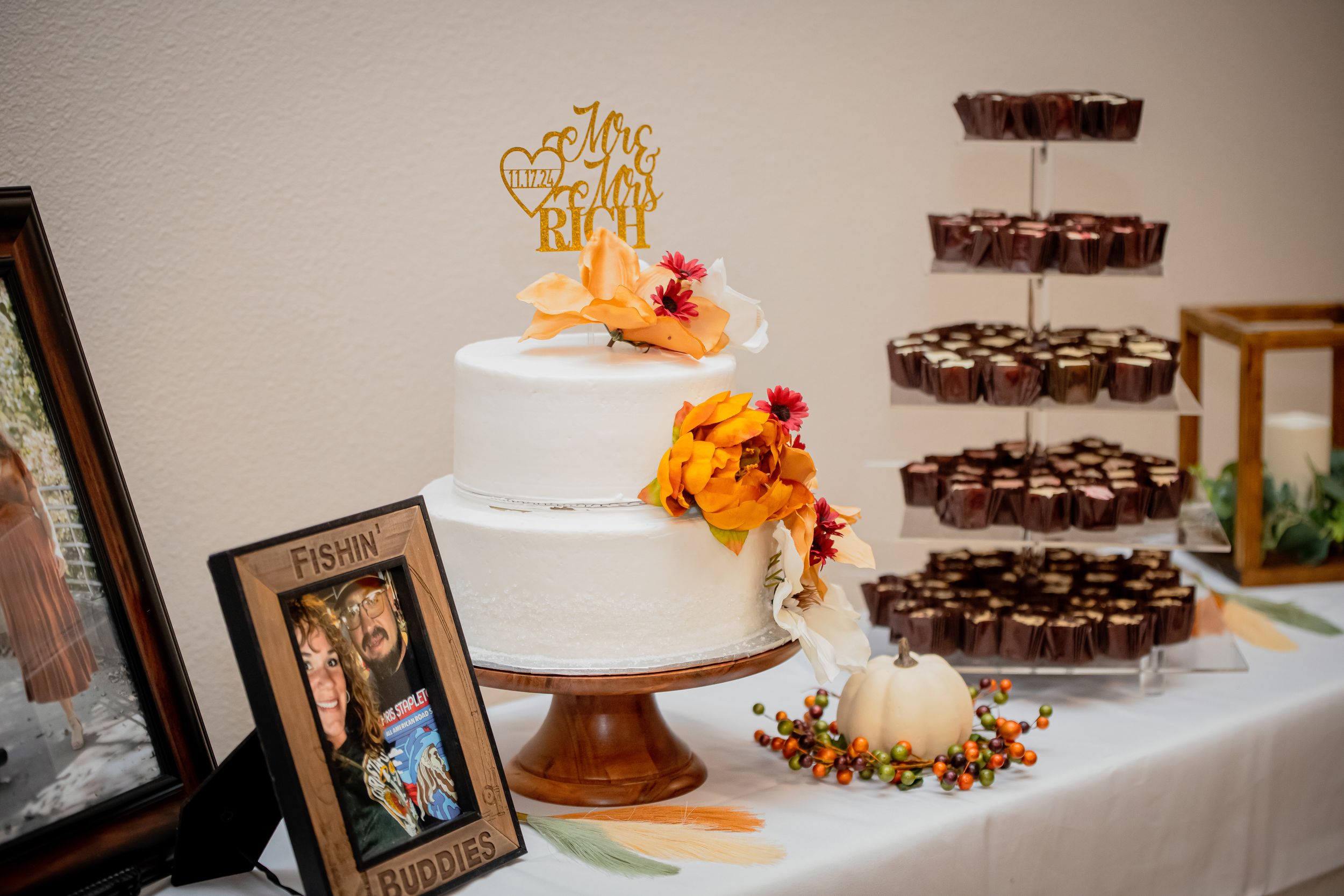 Wedding dessert table with chocolate tiers and orange floral decorations.