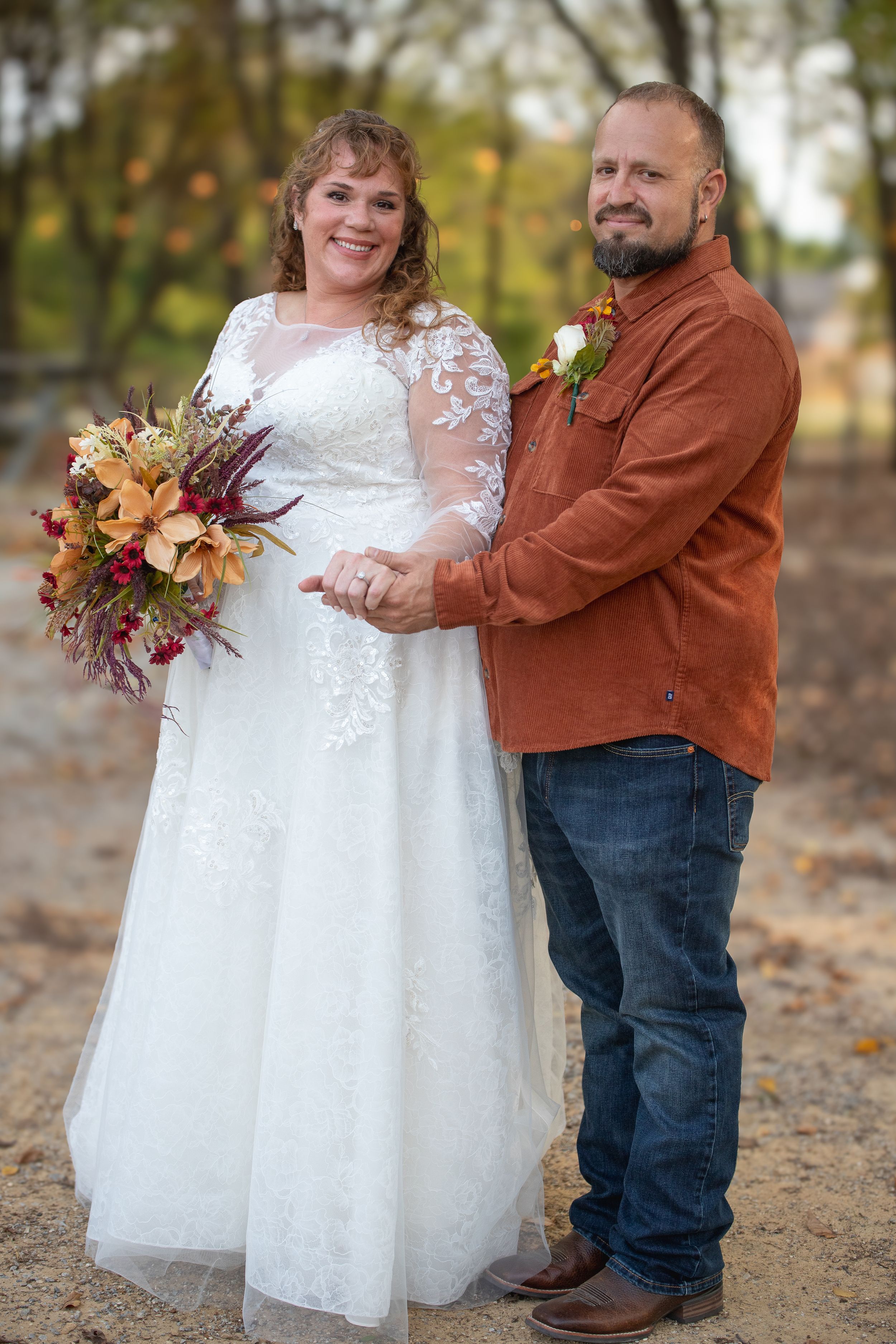 A couple embraces outdoors during an autumn wedding photoshoot.