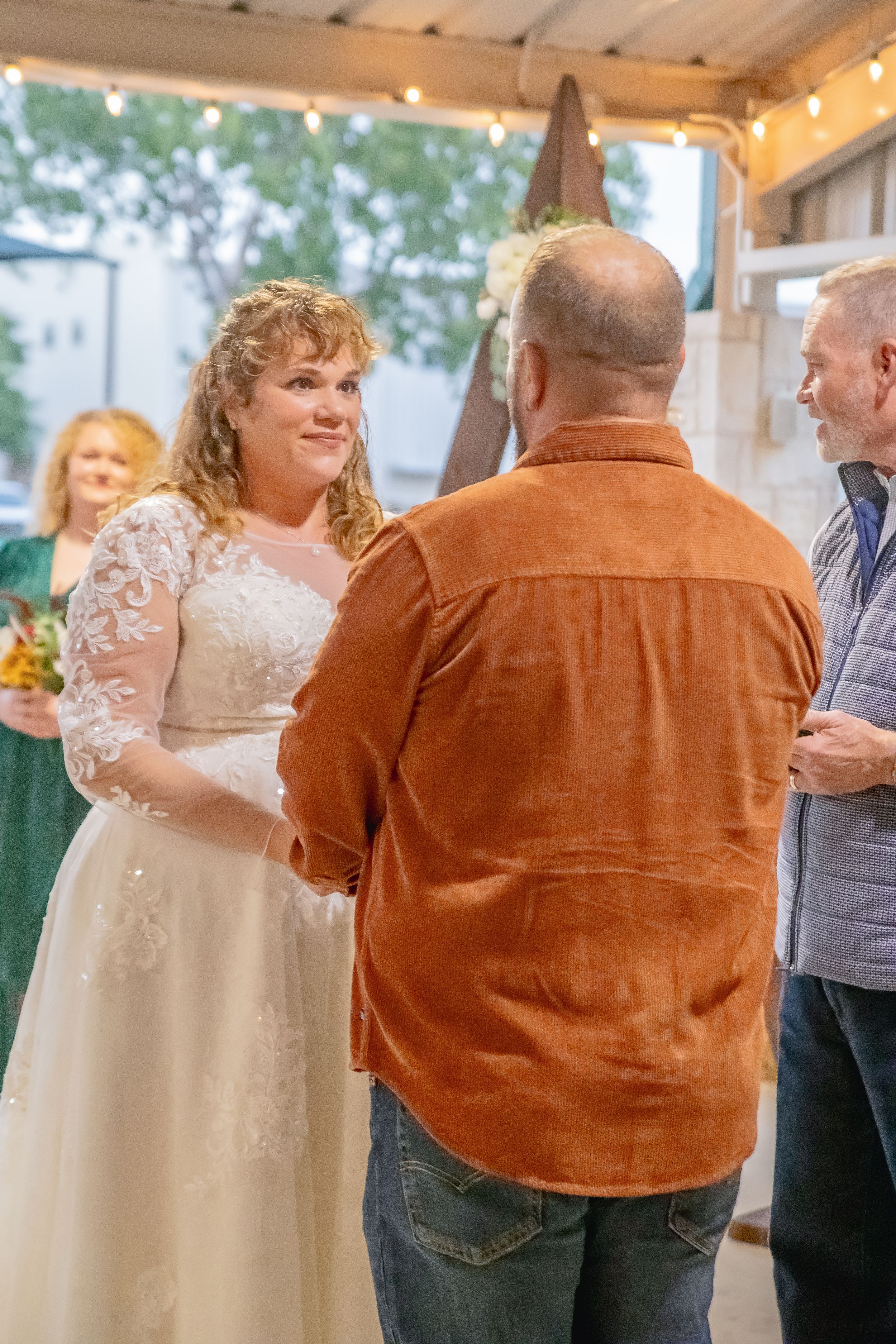 A couple dances under string lights at an outdoor covered venue.