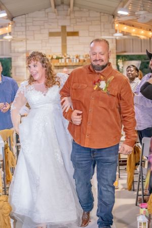 Dance sequence in rustic venue showing white wedding dress and brown jacket against stone backdrop.