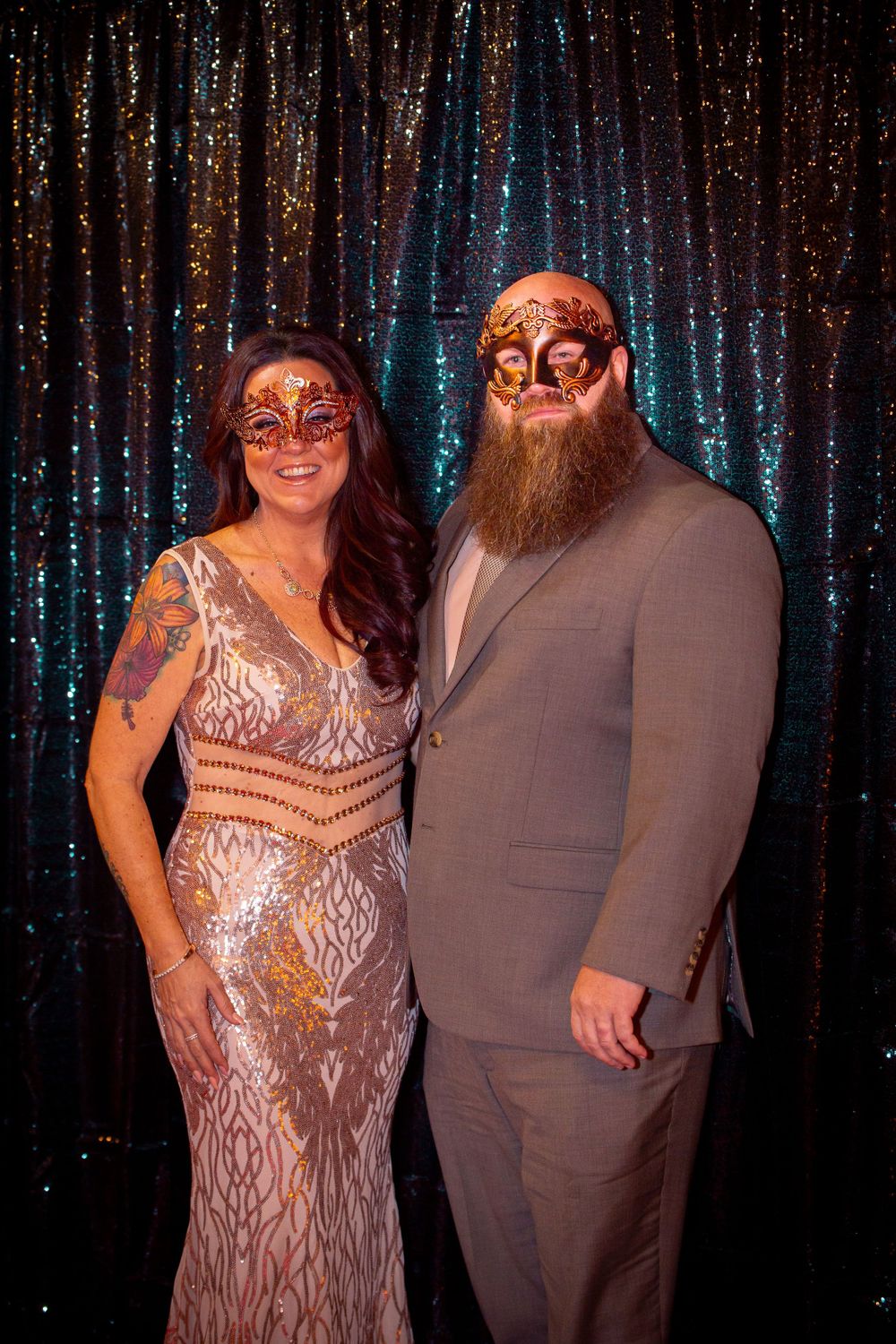 Couples posing in formal attire against a shimmering blue sequin backdrop.