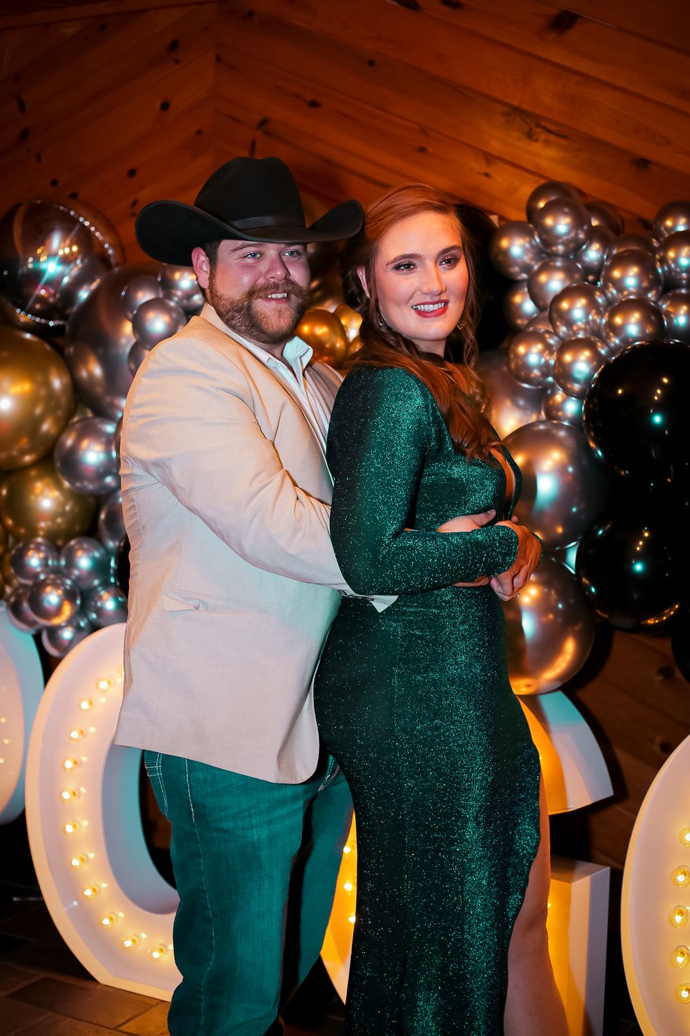 Couples dancing at an event with silver balloon decorations and illuminated letters in the background.