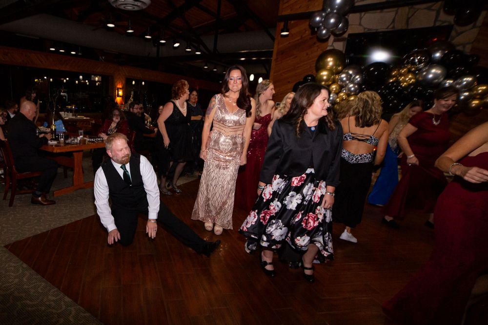 People dancing at a dimly lit indoor reception venue.