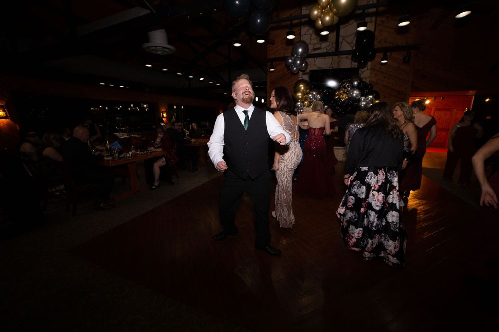 People dancing in a dimly lit reception hall.