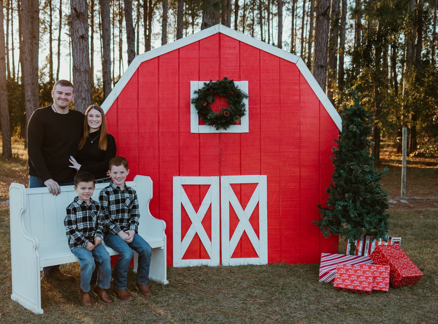 Christmas mini with a red barn, bench, Christmas tree, and gifts.